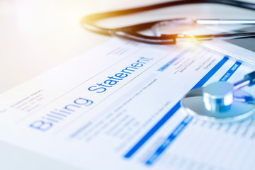 Close-up of a medical billing statement with a stethoscope placed on top, symbolizing healthcare costs and financial paperwork.